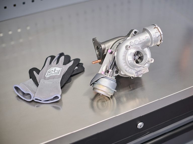 turbocharger components and mechanics' gloves placed on a workbench