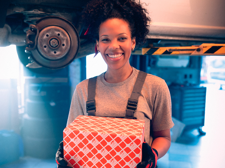 female mechanic in a workshop holding a febi box in her hands
